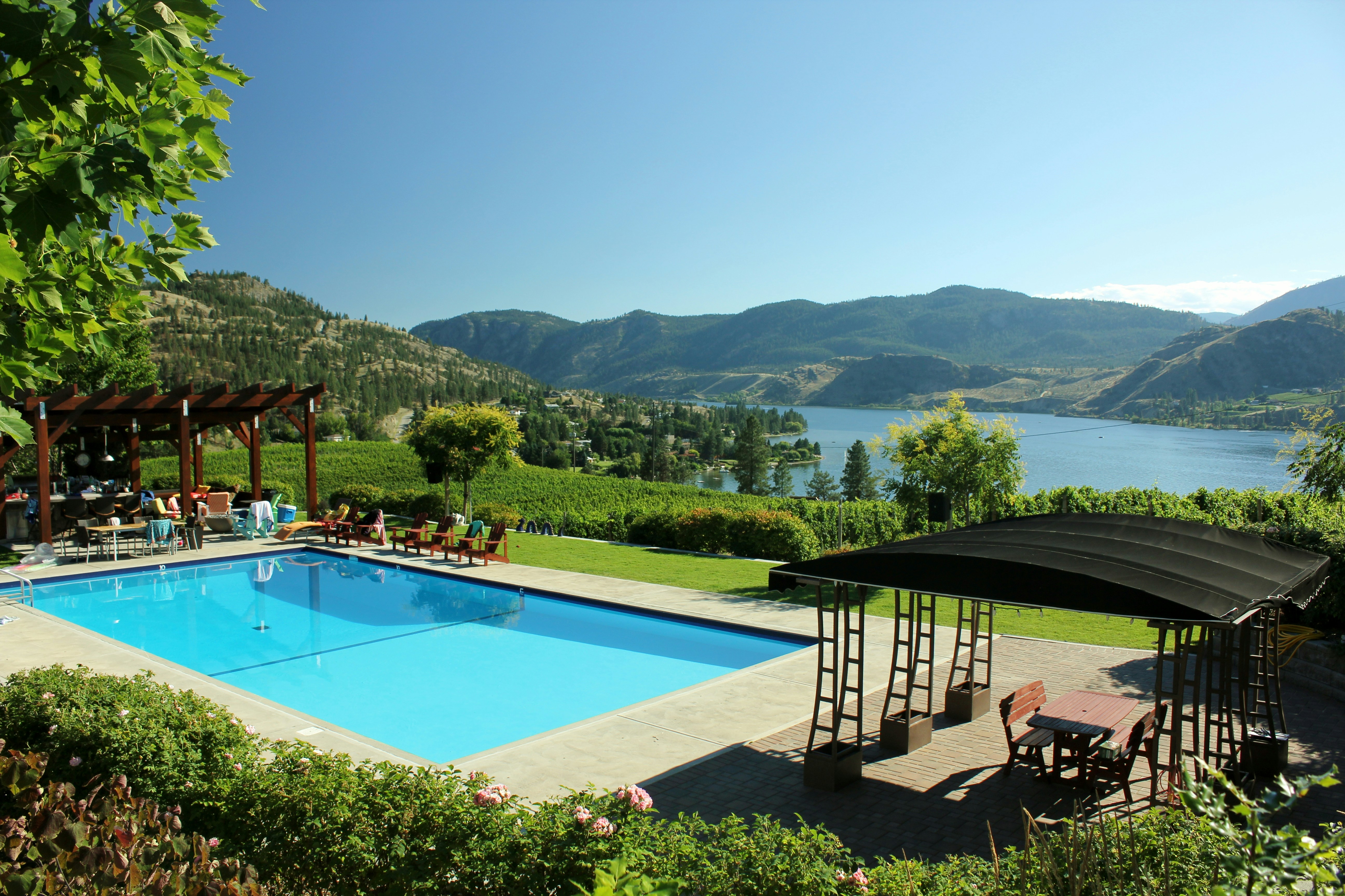 View of Okanagan lake in the summer with swimming pool in the foreground.